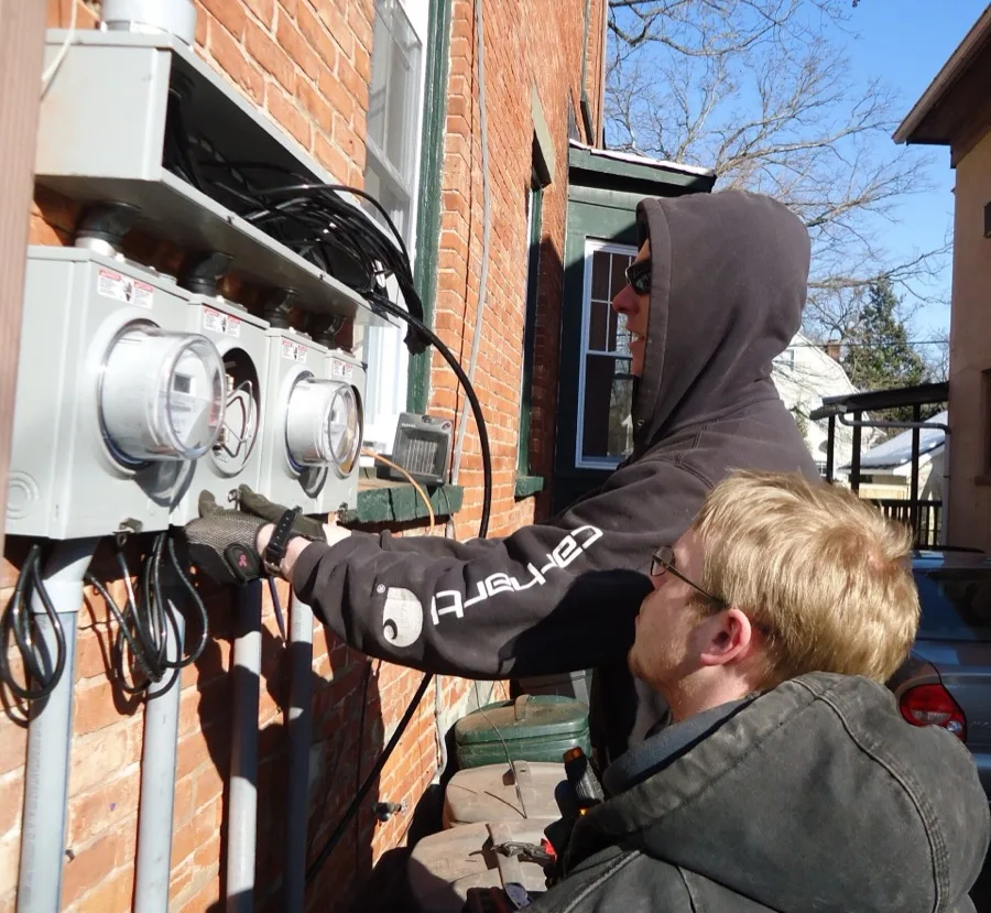 Electricians installing separate meter panels on a multi-family property