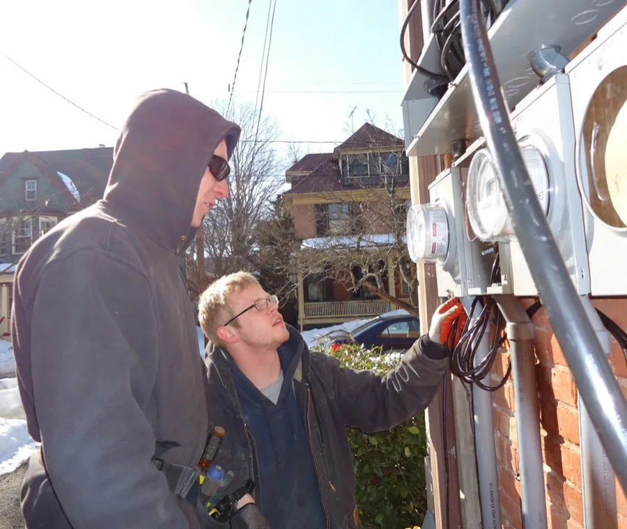 Two electricians collaborating on a panel installation